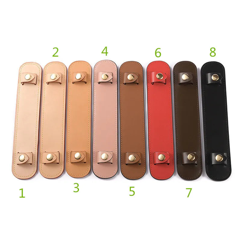 Eight leather handbag handle wraps and shoulder pads in various shades of tan, pink, brown, and black.