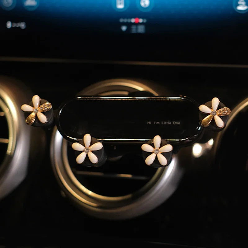 A crystal flower gravity car phone holder with auto-lock featuring white and gold accents.