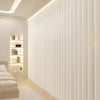 A vertical pleated white fabric room divider curtain with hooks in a modern bedroom setting.