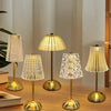A collection of four gold-toned crystal touch table lamps with amber glass shades displayed on a wooden surface.