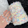 A hand is holding a fluffy, variegated yarn blend featuring pastel pink, blue, and yellow fibers.
