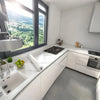 Modern kitchen featuring white marble countertops and cabinetry with a large window view.