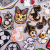 A collection of embroidered iron-on patches featuring various funny cartoon and animal designs like cats, a bat, and a duck.