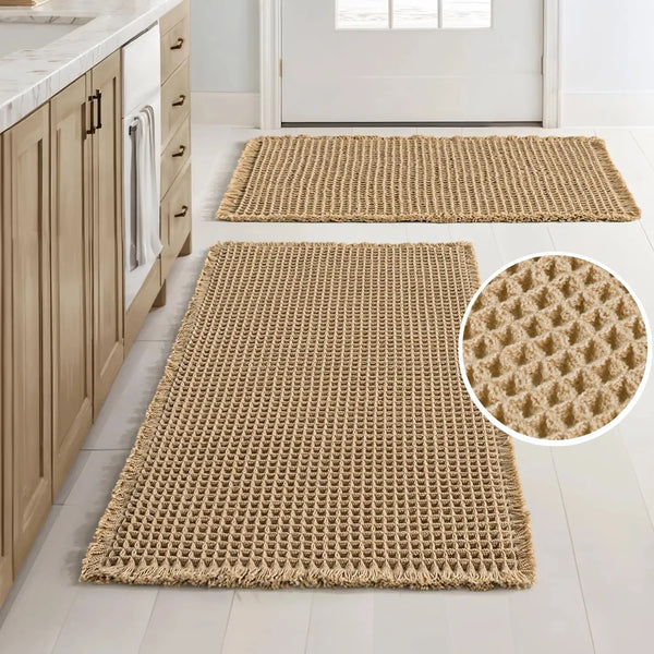 A rectangular beige waffle weave bath mat with a textured surface and non-slip backing placed on a light floor.