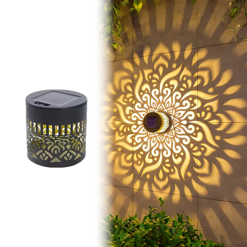 Una lámpara solar exterior oscura proyecta un patrón de mandala floral en una pared texturizada.