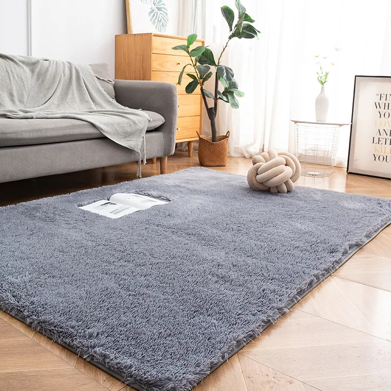 A gray Nordic furry accent rug placed on a light wood floor in a bright living room setting.