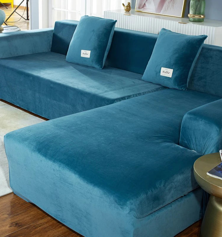 A deep teal plush velvet elastic sofa cover is shown on an L-shaped sofa with decorative throw pillows.