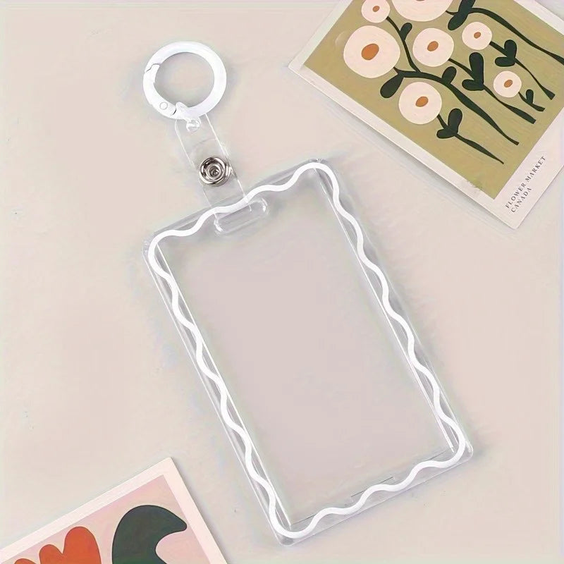 Sujetador de tarjetas de acrílico transparente con borde decorativo y anillo para llaves, apoyado sobre una superficie clara.