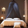 A dark blue ceiling-hung dome mosquito net draped over a bed in a bedroom setting.