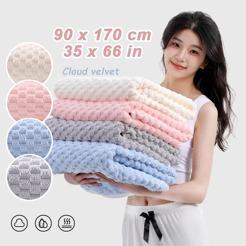 A woman holds a stack of pink and blue cloud velvet bath towels with a white top.