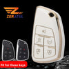 A white car key fob cover is shown next to two black key fobs on a dark surface.
