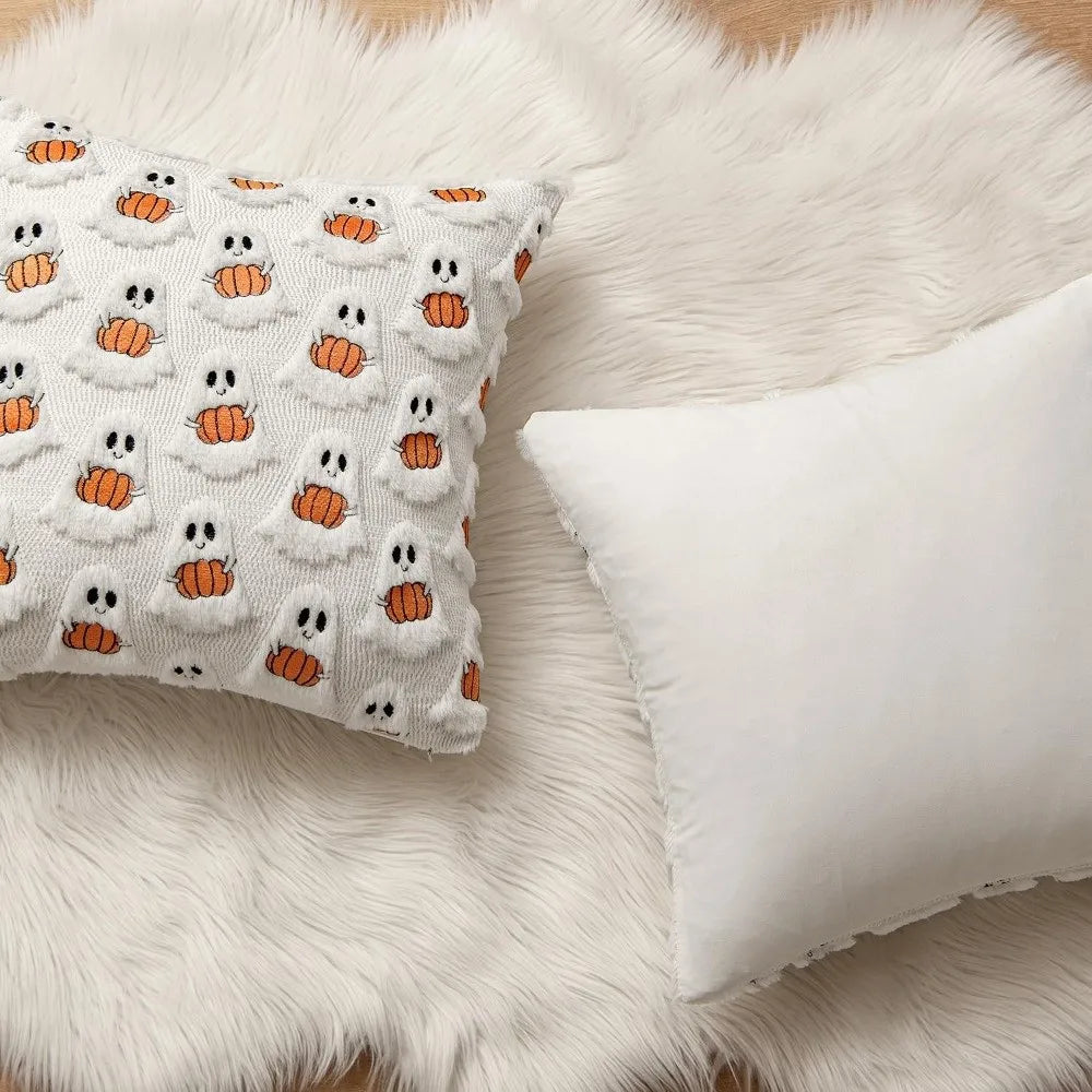 A white throw pillow cover featuring repeating orange Halloween ghost and pumpkin designs on a fluffy white rug.
