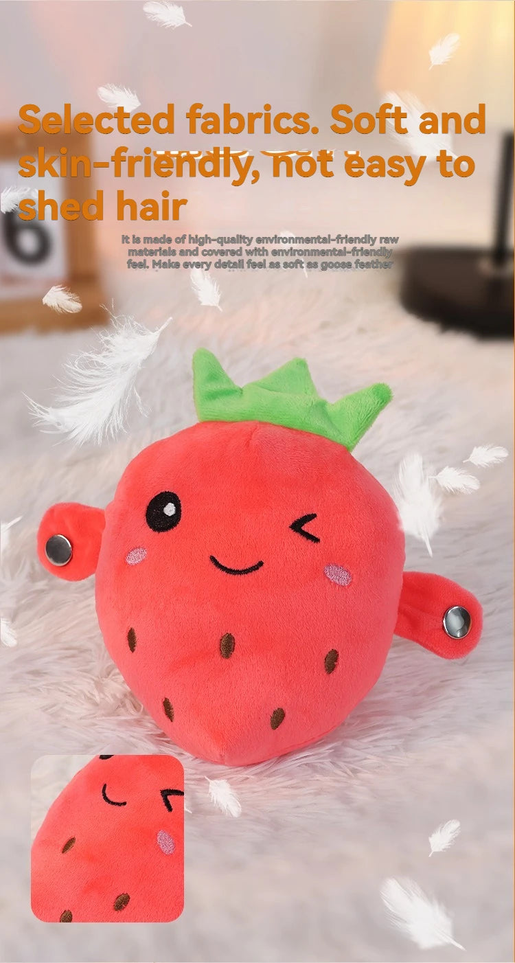 A bright red strawberry shaped plush toy with green leaves and a smiling face resting on a white fluffy surface.