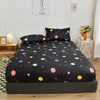 Black fitted bed sheet with a marbled print and all-around elastic band displayed on a bed.