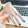 A hand holds a light pink resin Halloween hand planter and pen holder against a white laptop background.