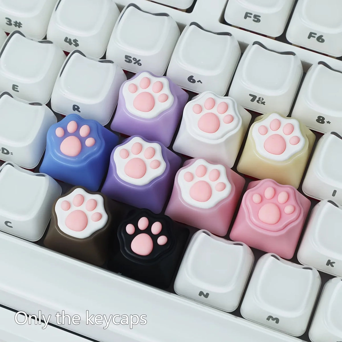 A collection of silicone keycaps shaped like cat paws and pink hearts for MX switches in various pastel colors.
