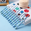 A set of ergonomic crochet hooks with a blue and white bee design laid out on a light blue surface next to a ball of yarn.