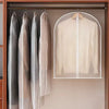 Three transparent zippered garment storage bags hanging in a wooden closet rack.