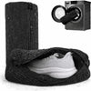 A black reusable shoe washing bag containing a white athletic shoe, next to a black and silver light box.