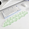 A light green, cloud-shaped ergonomic wrist rest set for a keyboard and mouse is displayed on a white desk.