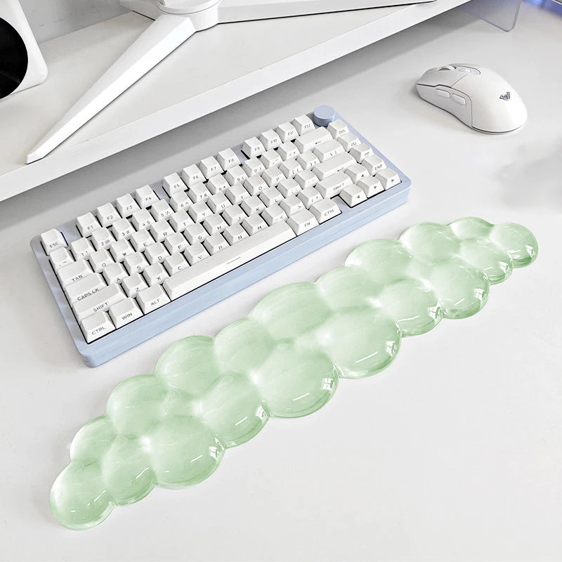 A light green, cloud-shaped ergonomic wrist rest set for a keyboard and mouse is displayed on a white desk.