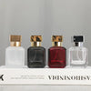 Four glass perfume bottles of varying colors and shapes displayed on a white box.