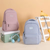 A pink and light blue waterproof nylon laptop backpack displayed on a white wooden shelf.