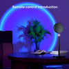 A black sunset lamp projector stands on a table with a green palm plant in the background.
