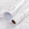 Roll of glossy pink marble contact paper for countertops lying on a white marble surface