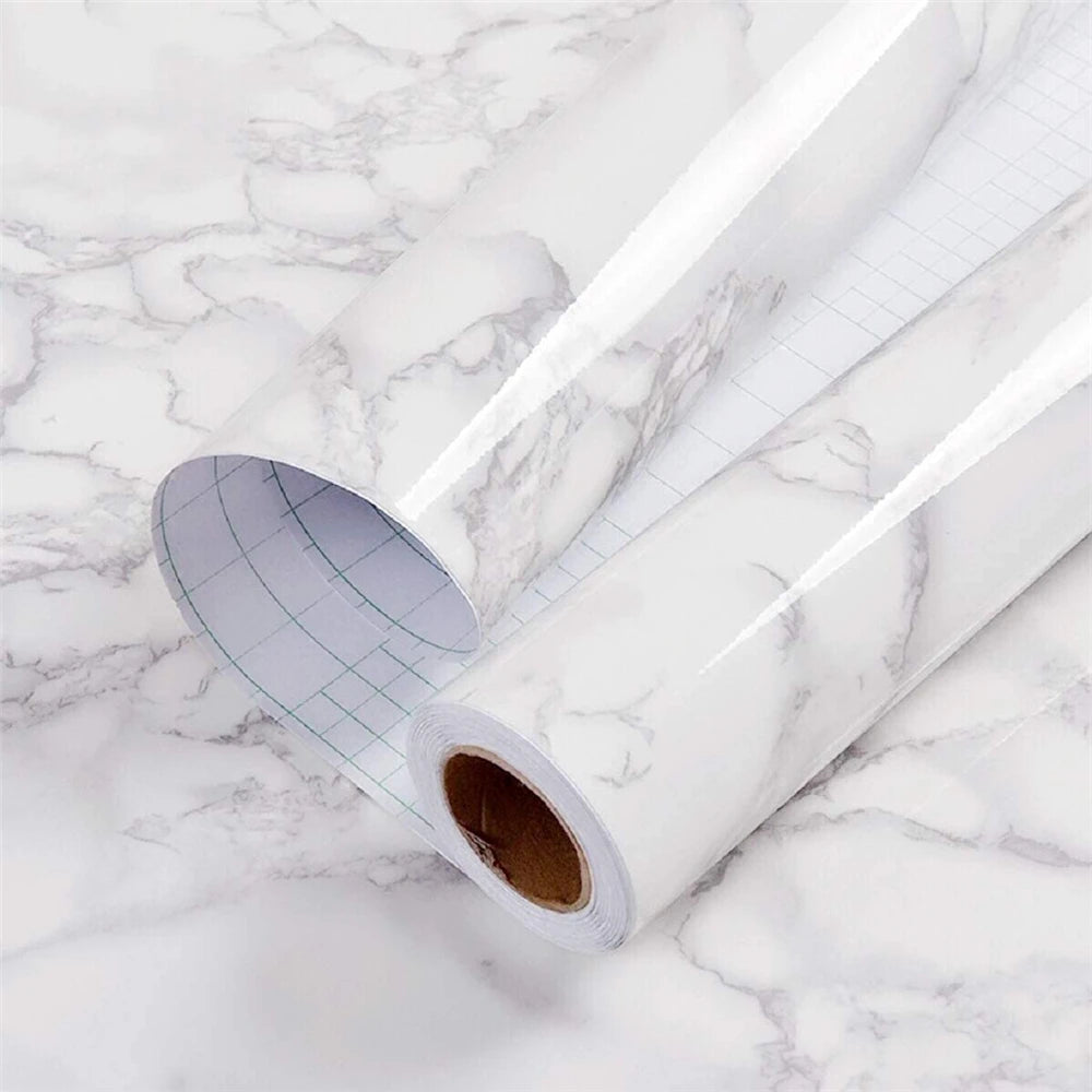 Roll of glossy pink marble contact paper for countertops lying on a white marble surface