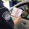 A Border Protection officer shows a car document organizer to a dog inside a vehicle.