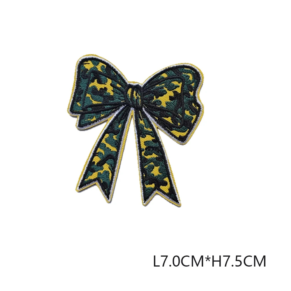 A dark green and yellow leopard print bow made of embroidered fabric.