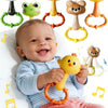A baby is holding a yellow cartoon animal rattle toy surrounded by various animal-themed sensory toys.