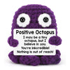 A handmade purple crochet octopus doll with a positive message card.