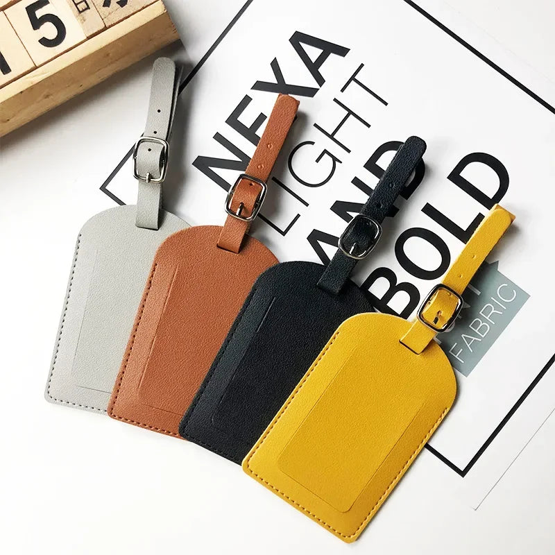 A collection of five classic PU leather luggage tags in various colors including gray, brown, black, and yellow