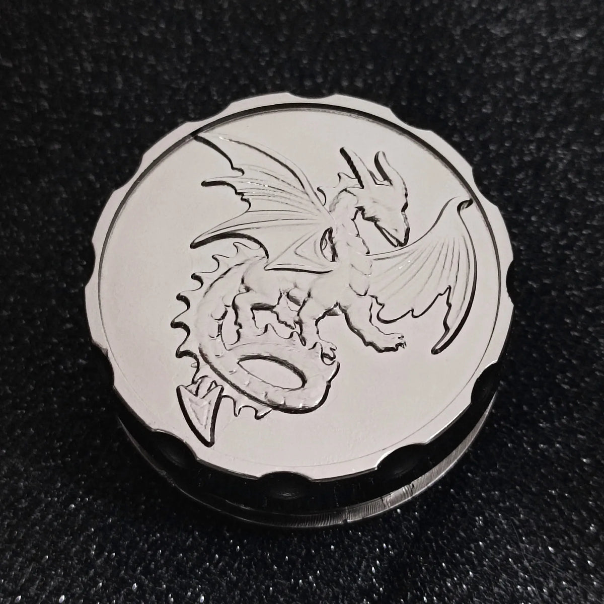 A silver metal coin featuring a detailed dragon design, used as a fingertip gyro roulette dice for tabletop games.