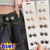 A set of nine gold and silver star-shaped metal brooch belt buckles displayed on a white card against a dark denim background