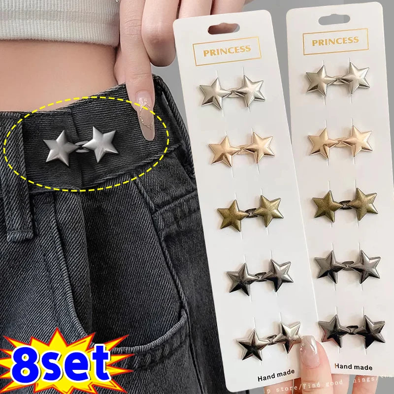 A set of nine gold and silver star-shaped metal brooch belt buckles displayed on a white card against a dark denim background