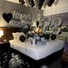 A balloon garland featuring black and silver balloons with oversized foil numbers decorating a room.