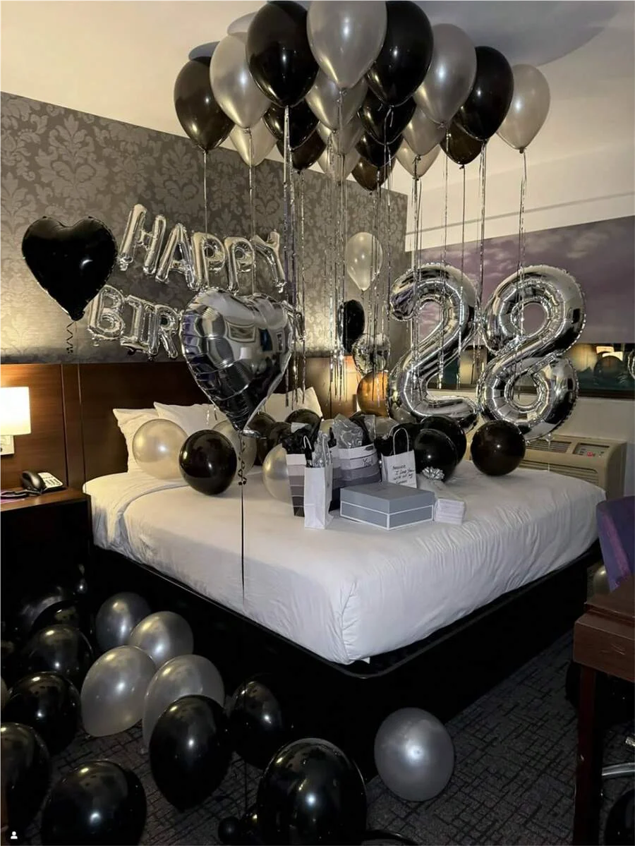 A balloon garland featuring black and silver balloons with oversized foil numbers decorating a room.