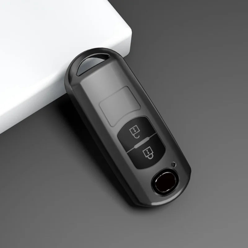 A close-up view of a black TPU car key cover resting on a white surface.