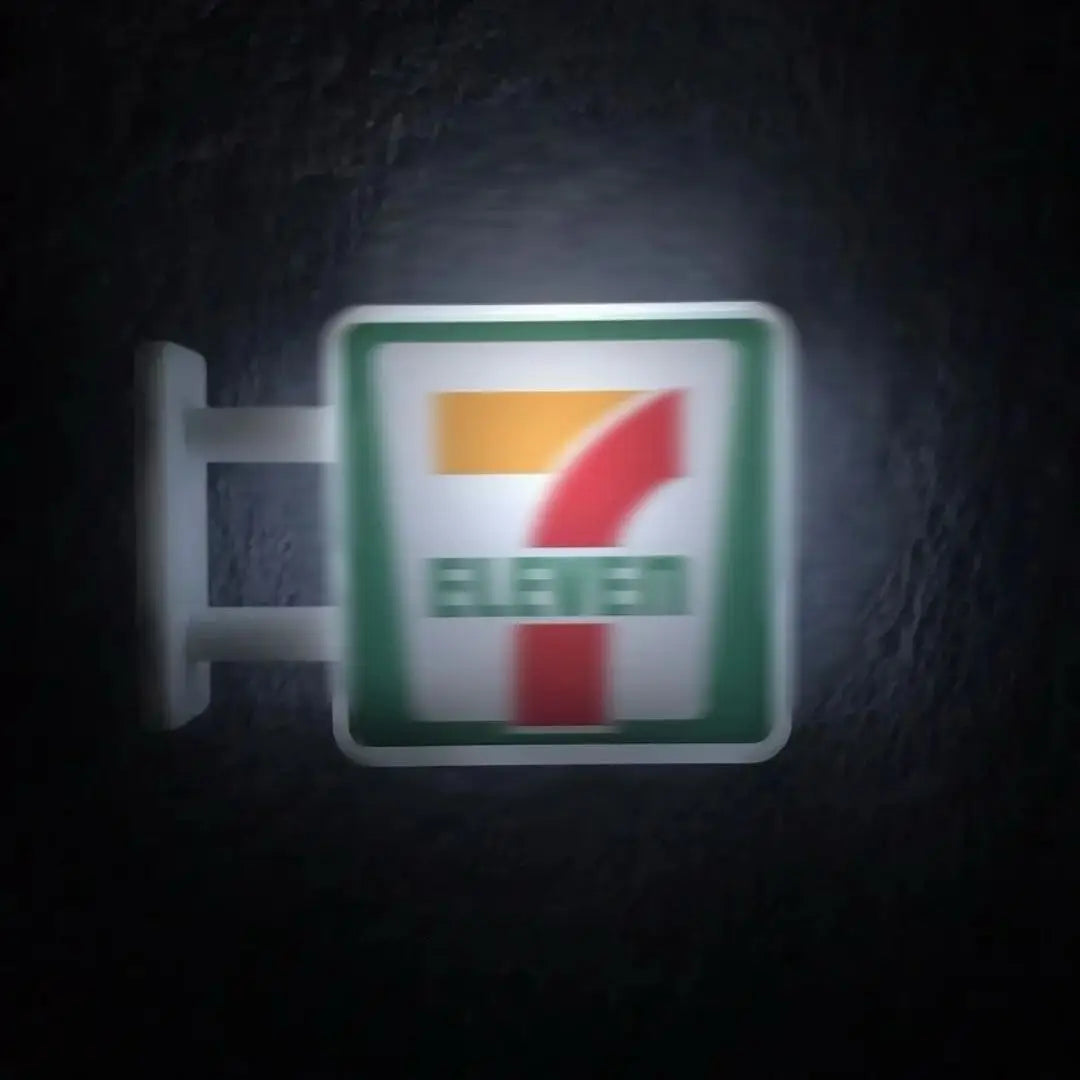 A miniature glowing storefront fridge magnet featuring the number seven and the word eleven on a green background.