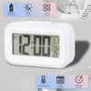 A white compact LED digital alarm clock displaying 12:00, with options for battery power, night light, temperature, date disp