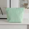 Pochette en crochet rayée vert clair posée sur une surface blanche.