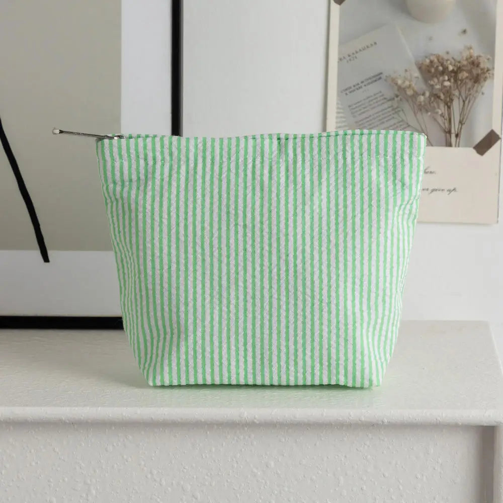 Pochette en crochet rayée vert clair posée sur une surface blanche.
