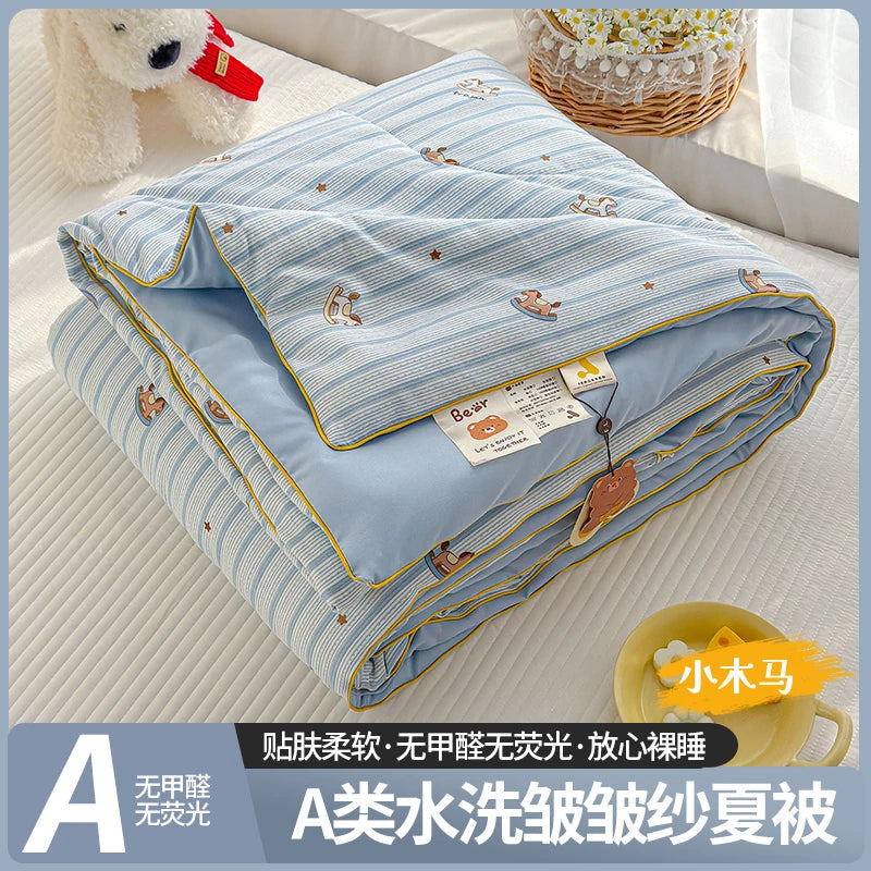 A blue and white striped quilt with a playful cartoon print, folded and displayed on a light surface.