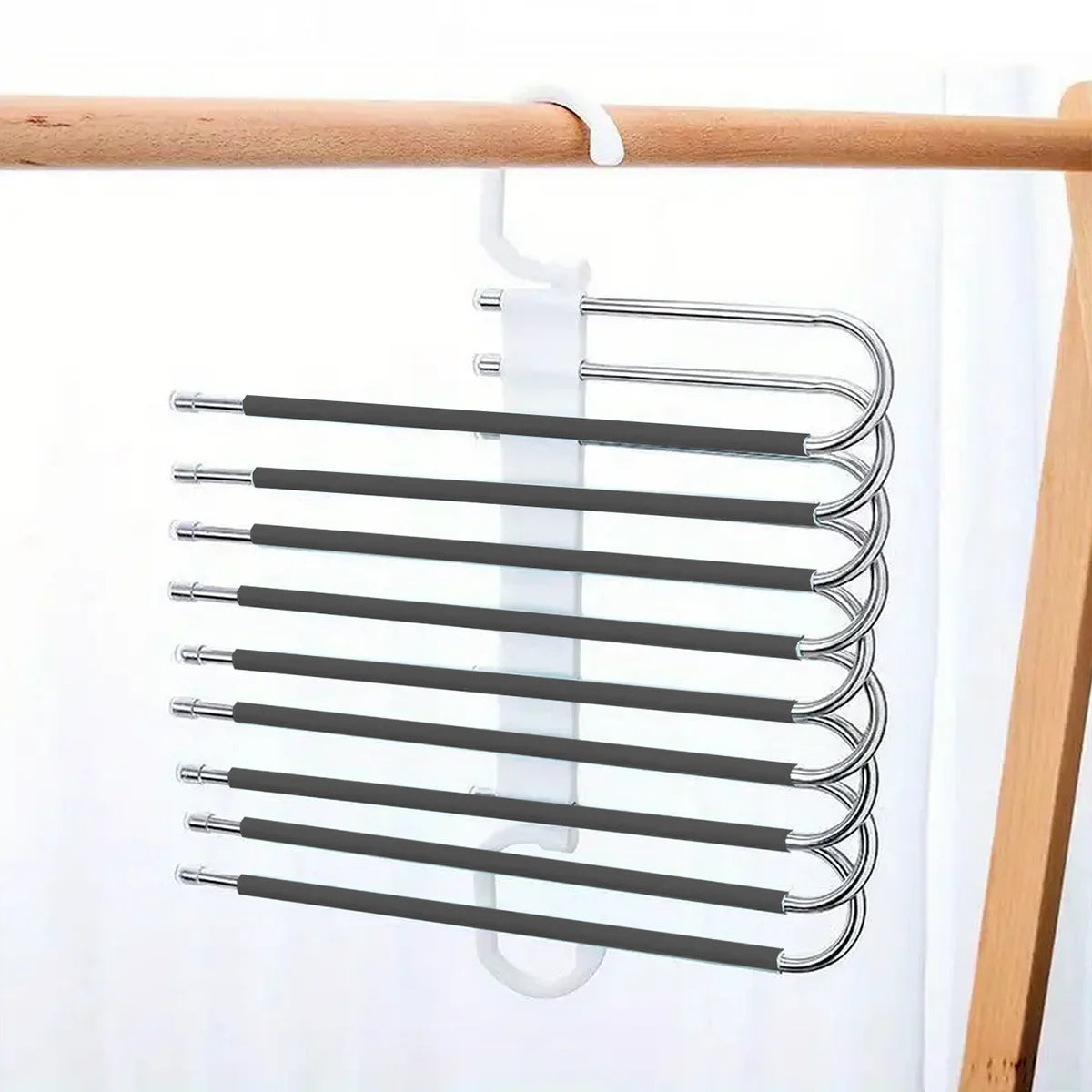 A rack of nine black stainless steel pants hangers hanging from a wooden bar.