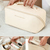 A beige leather travel makeup organizer bag is shown being held by a hand, with an open version visible nearby.