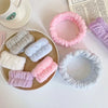 A collection of pink, purple, and white microfiber wrist sweatbands and scrunchies displayed on a white surface.