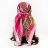 A vibrant pink leopard and paisley square scarf tied around a dark hairstyle.